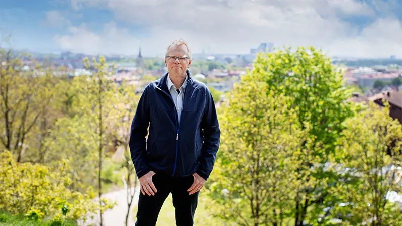 Jörgen Johansson står på Galgberget framför lummiga trädkronor och Halmstads takåsar.