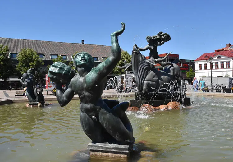 En naken kvinna rider på en tjur. I förgrunden syns en manlig figur, en triton. De står i en fontän.