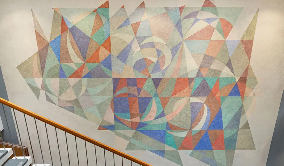 En väggmålning i en trappa. Abstrakta trianglar och andra former bildar en helhet i rött, grönt och blå färger. 
