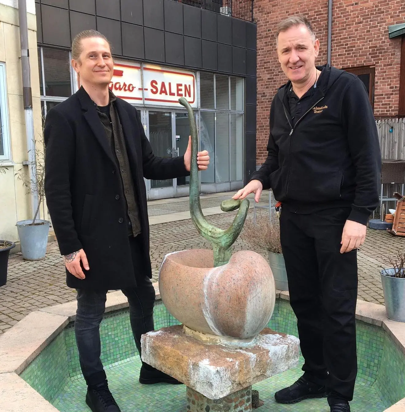 Joacim Eneroth, intendent för offentlig konst och Samir Katadzic, koordinator på Halmstad Teater vid Bernard Anderssons fontän Musikens källa med den återbördade bronslyran.