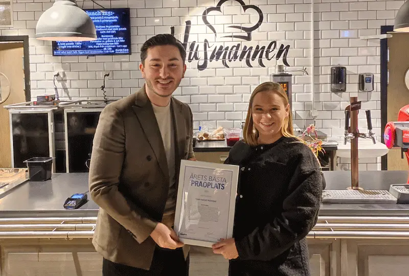 Barn- och ungdomsförvaltningens ordförande Arber Gashi lämna över ett diplom till Julia Andersson som är restaurangchef på Food market.