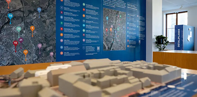 I bakgrunden syns en karta med utpekade nya bostadsområden och i förgrunden är ett av bostadsområdena utskrivet i 3D.